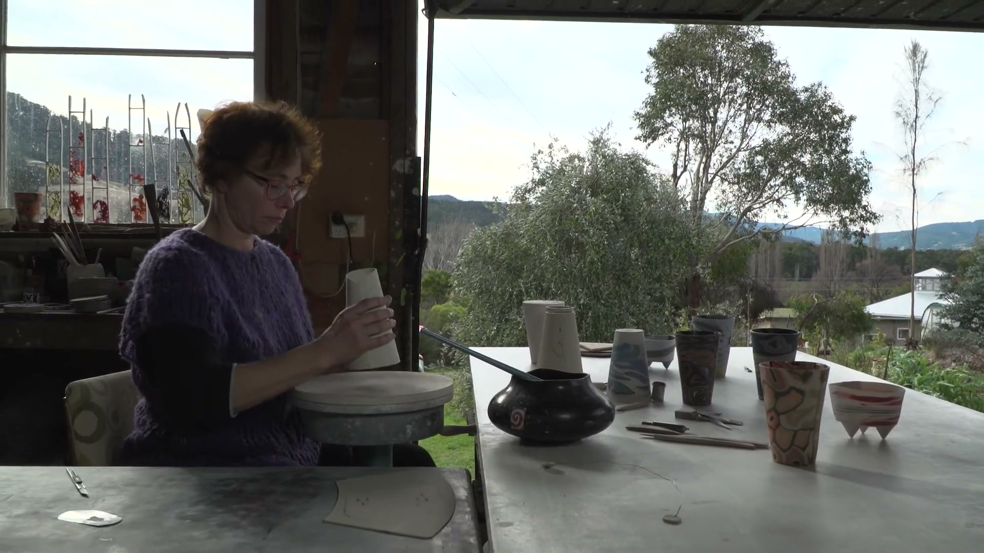 Abstract ceramic sculpture in Tasmanian bushland — earthy tones blending with eucalyptus greens